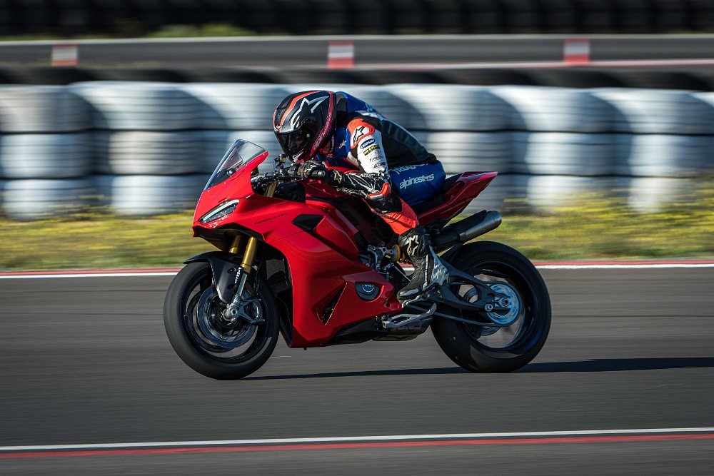 2025 Ducati Panigale V2 riding by in profile, on a race track.