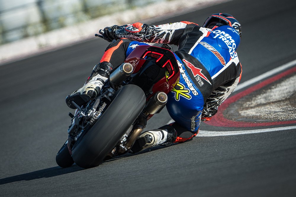 2025 Ducati Panigale V2 riding away from camera through a right-hand curve on a race track.