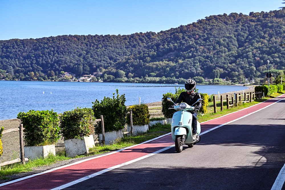 rider on a scooter beside a lake