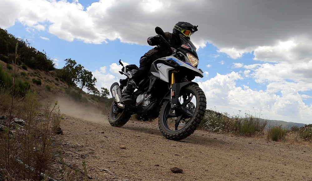 A female rider is riding in a standing position on the BMW G 310 GS on a truck trail