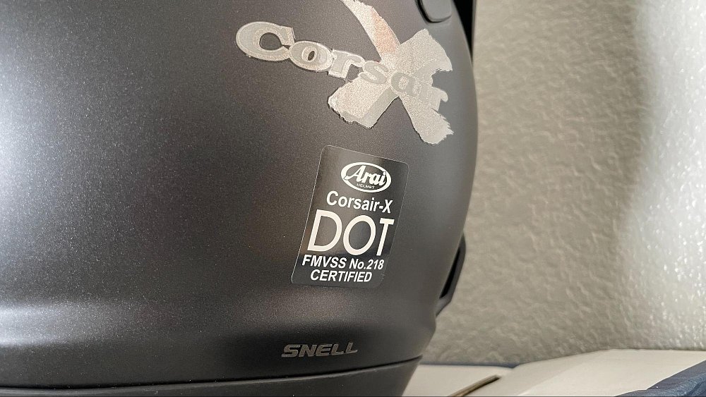 A close up of the DOT sticker on the back of a black Arai helmet