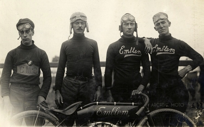 a black and white photo of a team of motorcycle racers wearing only leather helmets or casual caps with goggles