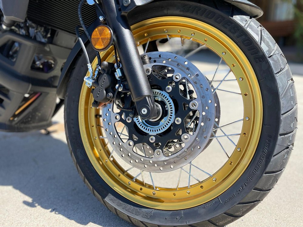 A close up of gold anodized, spoked tubeless wheels on V-Strom