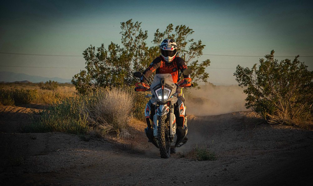2021 KTM 890 Adventure R Rally landing off a small jump on a motocross track in the desert.