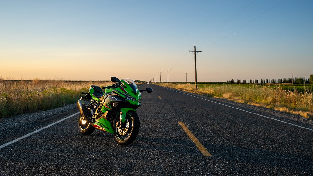 A 2023 Kawasaki ZX-4RR parked on a straight, country road at sunset.