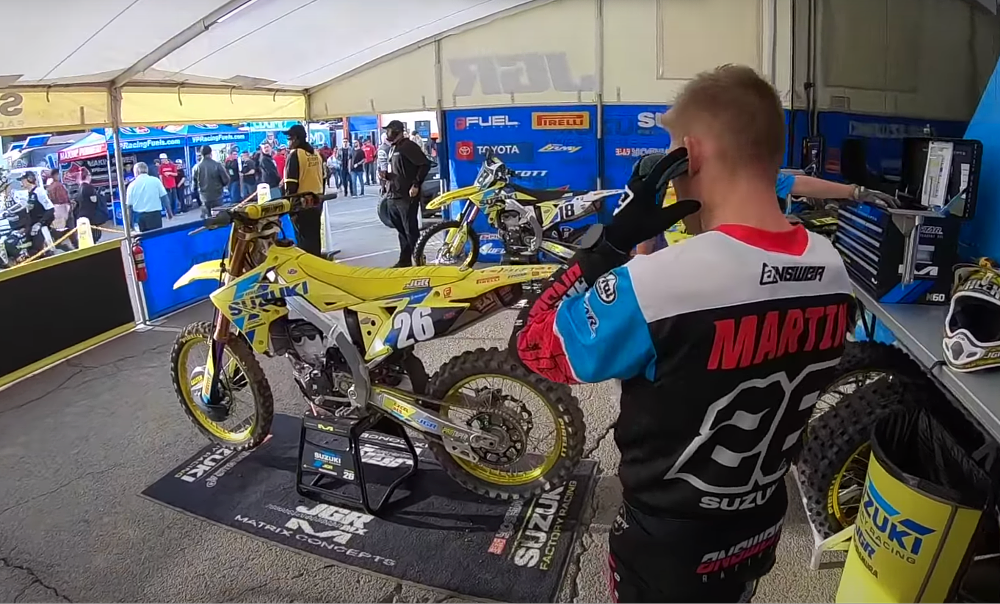 Alex Martin prepares to mount his yellow suzuki racebike