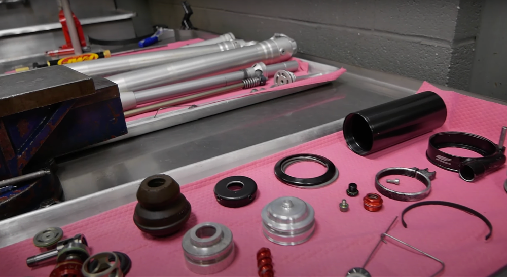 a variety of tools and components for suspension tuning on a metal work bench