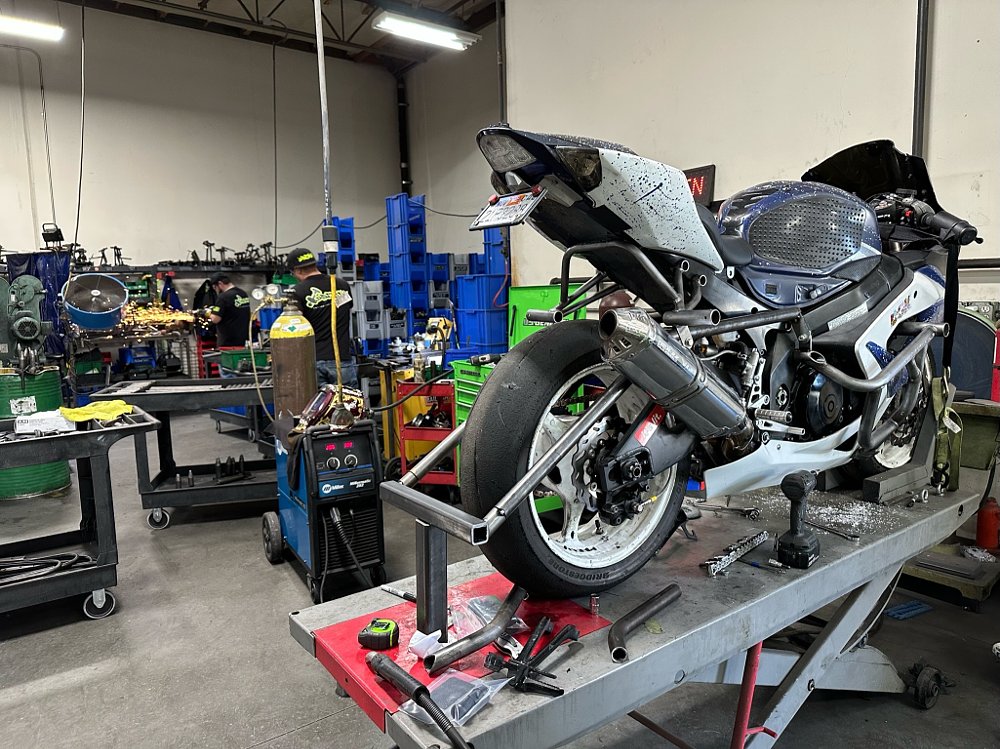 A 2006 Suzuki GSX-R1000 sits on a lift while a trailer hitch is installed.