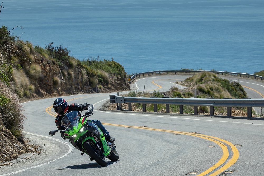 Ninja 500 on a curving moutaing road with the ocean in the background