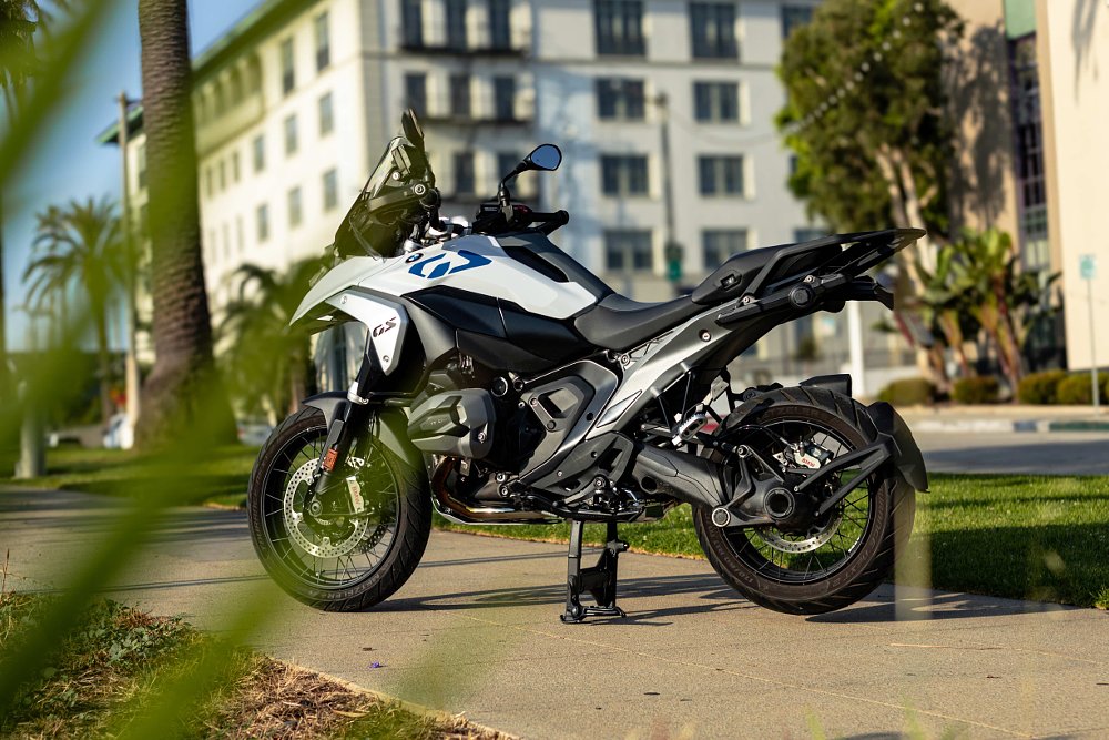 2024 BMW R 1300 GS parked in a city with plant leaves in the foreground.
