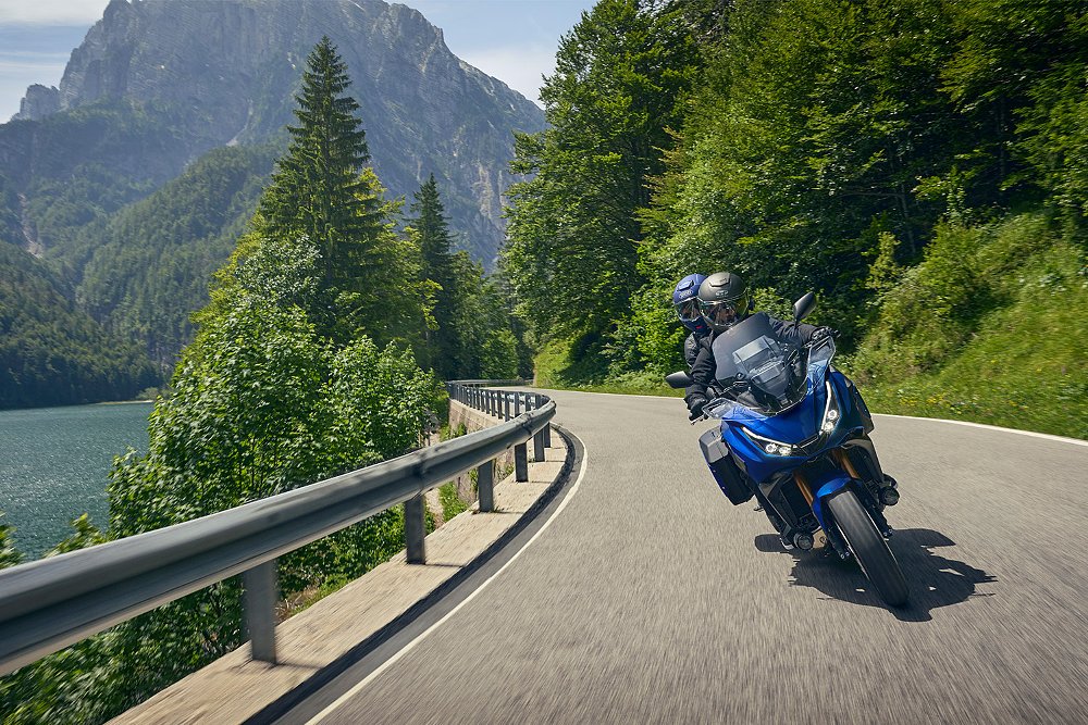 A couple rides the Honda NT1100 two-up along a mountainous road.